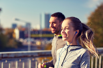 Image showing happy couple with earphones running in city