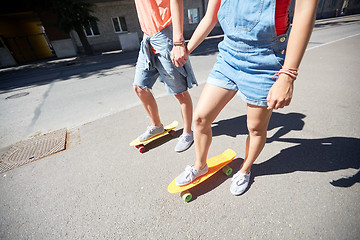 Image showing teenage couple riding skateboards on city street