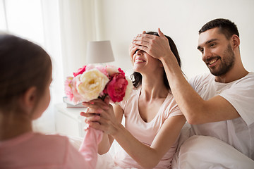 Image showing happy girl giving flowers to mother in bed at home