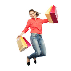 Image showing smiling young woman with shopping bags jumping