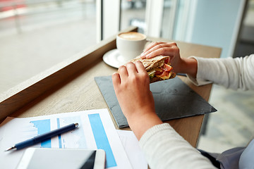 Image showing woman eating salmon panini sandwich at cafe