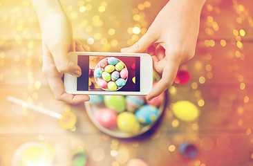 Image showing close up of hands with easter eggs and smartphone