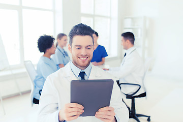 Image showing happy doctor with tablet pc over team at clinic