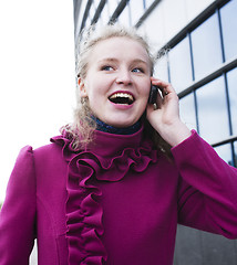 Image showing pretty blond woman talking emotional on phone outside near modern building, lifestyle people concept