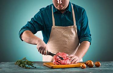 Image showing Butcher cutting pork meat on kitchen