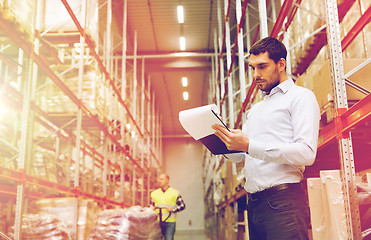 Image showing businessman writing to clipboard at warehouse