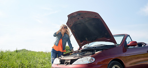 Image showing woman with open hood of broken car at countryside