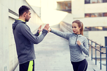 Image showing happy woman with coach working out strike outdoors