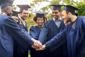 Image showing happy students in mortar boards with hands on top