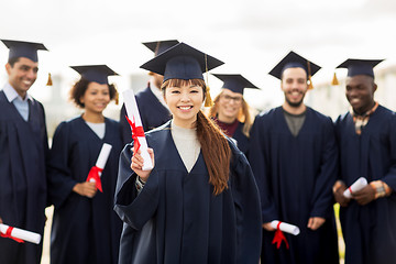 Image showing happy students in mortar boards with diplomas