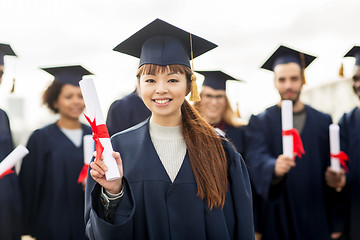 Image showing happy students in mortar boards with diplomas