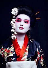 Image showing young pretty real geisha in kimono with sakura and decoration