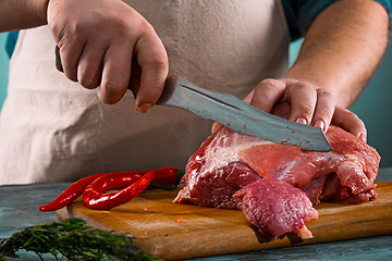 Image showing Butcher cutting pork meat on kitchen