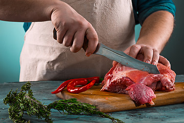 Image showing Butcher cutting pork meat on kitchen