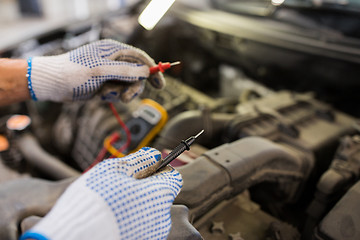 Image showing auto mechanic man with multimeter testing battery