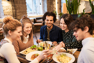 Image showing friends with smartphone eating at restaurant