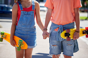 Image showing close up of young couple with skateboards in city