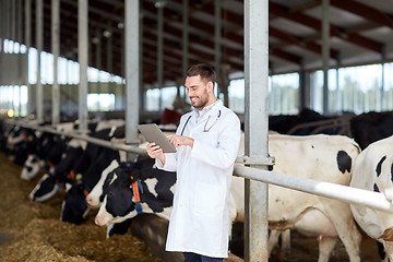 Image showing veterinarian with tablet pc and cows on dairy farm