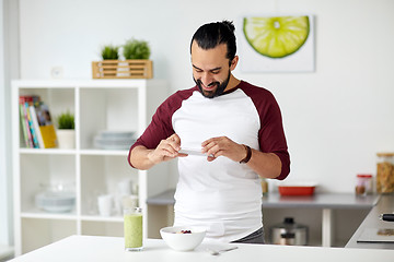 Image showing man photographing breakfast by smartphone at home