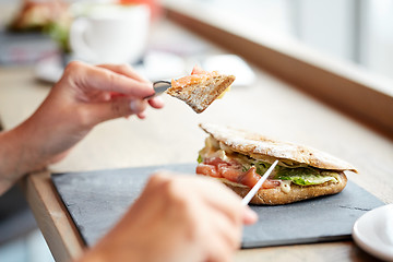 Image showing woman eating salmon panini sandwich at restaurant