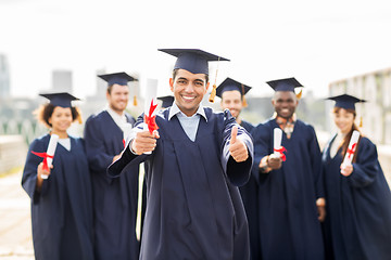 Image showing happy students with diplomas showing thumbs up