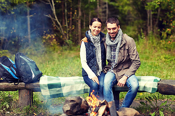 Image showing happy couple sitting on bench near camp fire