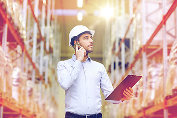 Image showing man with clipboard and smartphone at warehouse