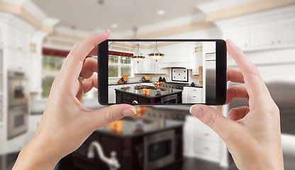 Image showing Female Hands Holding Smart Phone Displaying Photo of Kitchen Beh