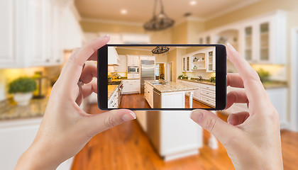 Image showing Female Hands Holding Smart Phone Displaying Photo of Kitchen Beh