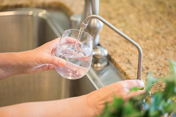 Image showing Woman Pouring Fresh Reverse Osmosis Purified Water Into Glass in