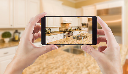 Image showing Female Hands Holding Smart Phone Displaying Photo of Kitchen Beh