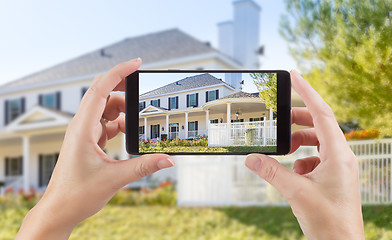 Image showing Female Hands Holding Smart Phone Displaying Photo of House Behin