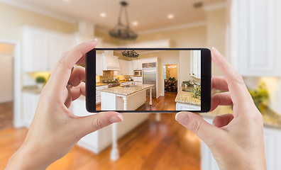 Image showing Female Hands Holding Smart Phone Displaying Photo of Kitchen Beh