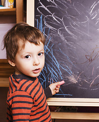 Image showing little cute boy with young teacher in classroom studying at blackboard smiling, doing homework