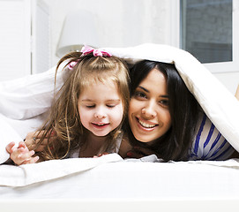 Image showing mother with daughter together in bed smiling, happy family close up, lifestyle people concept, cool real modern family playing