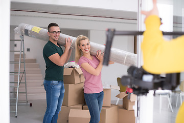 Image showing couple carrying a carpet moving in to new home