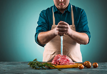 Image showing Butcher cutting pork meat on kitchen