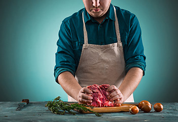 Image showing Butcher cutting pork meat on kitchen