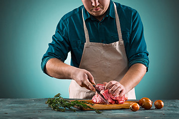 Image showing Butcher cutting pork meat on kitchen