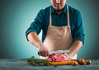 Image showing Butcher cutting pork meat on kitchen