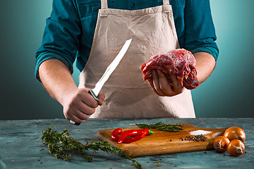 Image showing Butcher cutting pork meat on kitchen