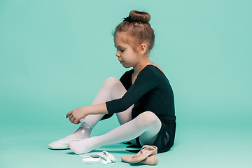 Image showing Beautiful little ballerina in black dress for dancing puting on foot pointe shoes