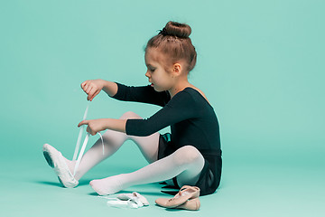 Image showing Beautiful little ballerina in black dress for dancing puting on foot pointe shoes