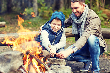 Image showing father and son roasting marshmallow over campfire