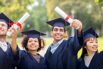 Image showing happy students in mortar boards with diplomas