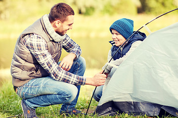 Image showing happy father and son setting up tent outdoors