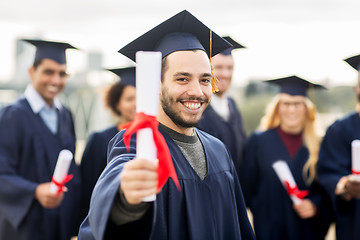 Image showing happy students in mortar boards with diplomas