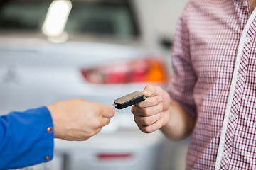 Image showing auto mechanic giving car key to man at workshop