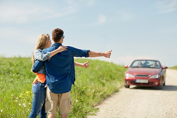 Image showing couple hitchhiking and stopping car on countryside