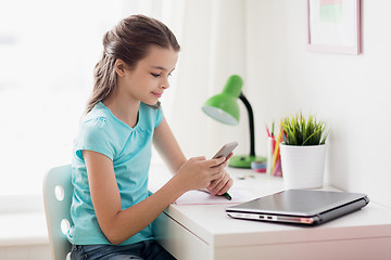 Image showing girl with laptop and smartphone texting at home